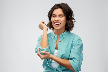 Image showing young woman in shirt suffering from pain in hand