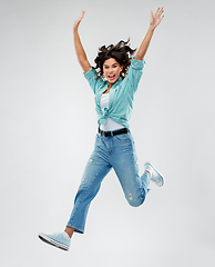 Image showing happy young woman jumping over grey background