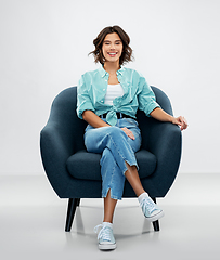 Image showing happy smiling young woman sitting in armchair