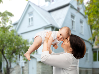 Image showing happy middle-aged mother with baby over house