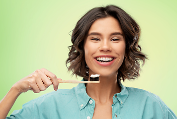 Image showing smiling woman with toothpaste on wooden toothbrush