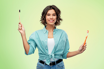 Image showing woman comparing wooden and plastic toothbrush