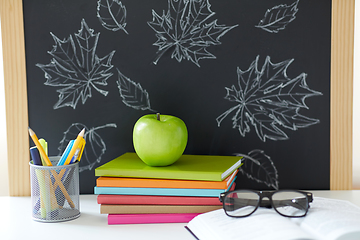 Image showing books, apple and school supplies on table at home