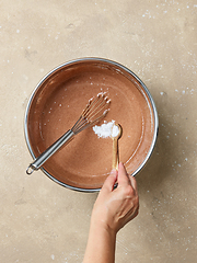 Image showing adding baking soda in a chocolate cake dough