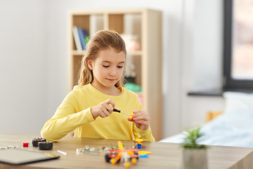 Image showing happy girl playing with robotics kit at home