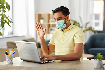 Image showing man in mask with laptop having video call at home