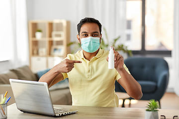 Image showing man in mask with hand sanitizer at home office