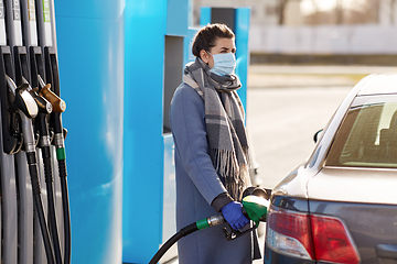 Image showing woman in mask filling her car at gas station