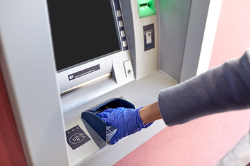 Image showing hand in medical glove entreing code at atm machine