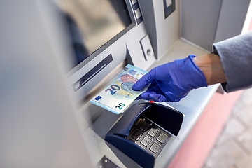 Image showing hand in medical glove with money at atm machine