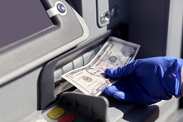 Image showing hand in medical glove with money at atm machine