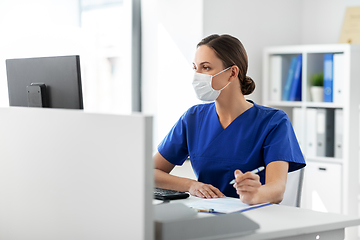 Image showing doctor or nurse in mask with clipboard at hospital