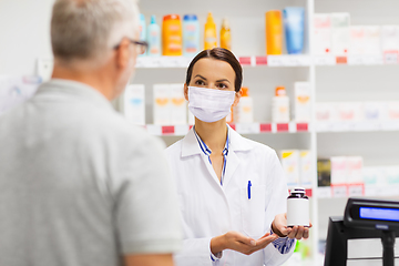 Image showing apothecary in mask showing drug to man at pharmacy