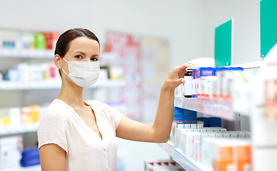 Image showing female customer in mask choosing drugs at pharmacy