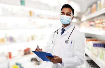 Image showing indian doctor in mask with clipboard at pharmacy