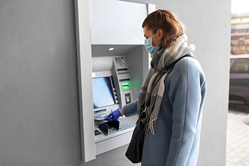 Image showing hand in medical glove with money at atm machine