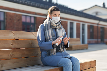 Image showing woman in mask spraying hand sanitizer outdoors