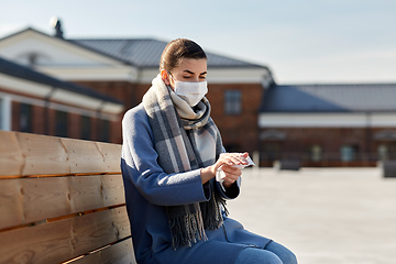 Image showing woman in mask cleaning hands with antiseptic wipe