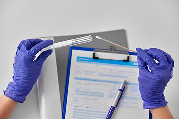 Image showing hands in gloves holding test tube and cotton swab