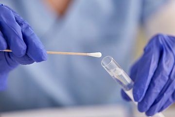 Image showing hands in gloves holding test tube and cotton swab