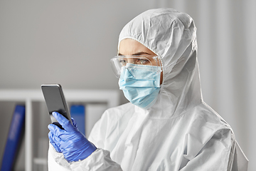 Image showing doctor in protective wear with smartphone