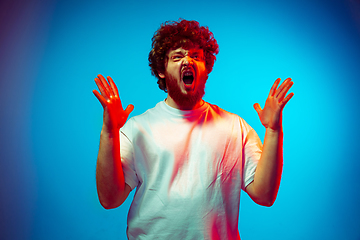 Image showing Caucasian man\'s portrait isolated on blue studio background in neon light