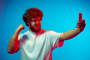 Image showing Caucasian man\'s portrait isolated on blue studio background in neon light