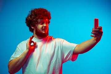 Image showing Caucasian man\'s portrait isolated on blue studio background in neon light