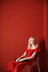 Image showing Young adult woman sitting on a chair and holding laptop