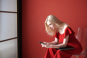 Image showing Young adult woman using smartphone and holding laptop