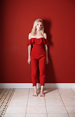 Image showing Beautiful young adult woman wearing red jumpsuit standing next t
