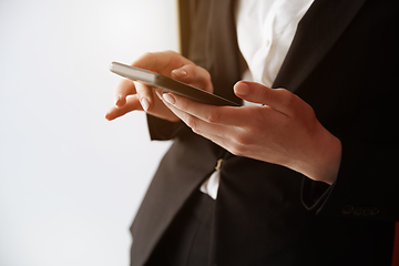 Image showing Young adult woman using smartphone next to the white wall