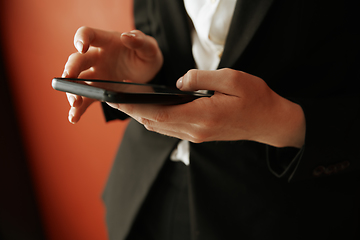 Image showing Young adult woman using smartphone next to the red wall