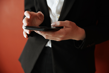 Image showing Young adult woman using smartphone next to the red wall