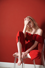 Image showing Beautiful young adult woman wearing red jumpsuit relaxing on cha