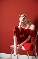 Image showing Beautiful young adult woman wearing red jumpsuit relaxing on cha