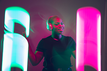 Image showing African-american young woman\'s portrait in headphone and bright neon lights