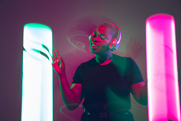 Image showing African-american young woman\'s portrait in headphone and bright neon lights