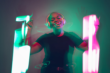 Image showing African-american young woman\'s portrait in headphone and bright neon lights