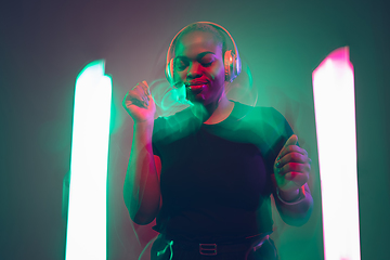 Image showing African-american young woman\'s portrait in headphone and bright neon lights