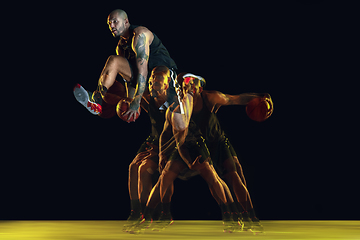 Image showing Young basketball player training on dark studio background in neon, strobe light