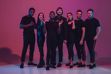 Image showing Group of young multiethnic musicians created band, dancing in neon light on pink background