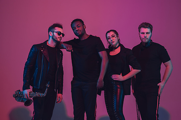 Image showing Group of young multiethnic musicians created band, dancing in neon light on pink background