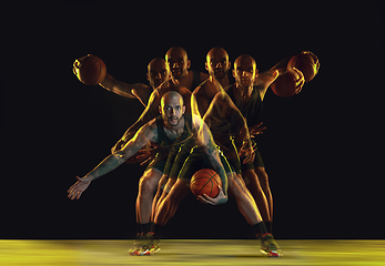 Image showing Young basketball player training on dark studio background in neon, strobe light