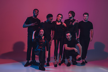 Image showing Group of young multiethnic musicians created band, dancing in neon light on pink background