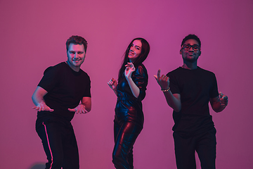 Image showing Group of young multiethnic musicians created band, dancing in neon light on pink background