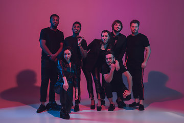 Image showing Group of young multiethnic musicians created band, dancing in neon light on pink background