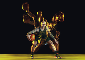 Image showing Young basketball player training on dark studio background in neon, strobe light