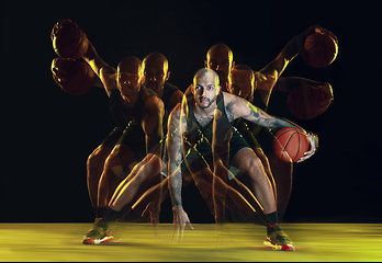 Image showing Young basketball player training on dark studio background in neon, strobe light