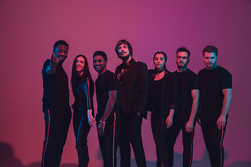 Image showing Group of young multiethnic musicians created band, dancing in neon light on pink background